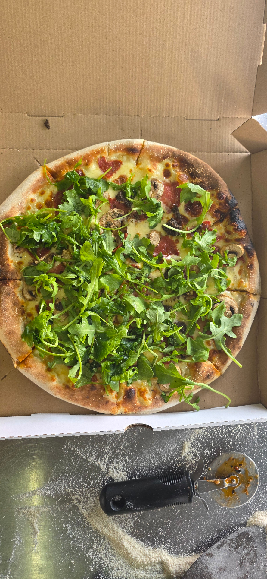 Wood-fired pizza topped with fresh rocket