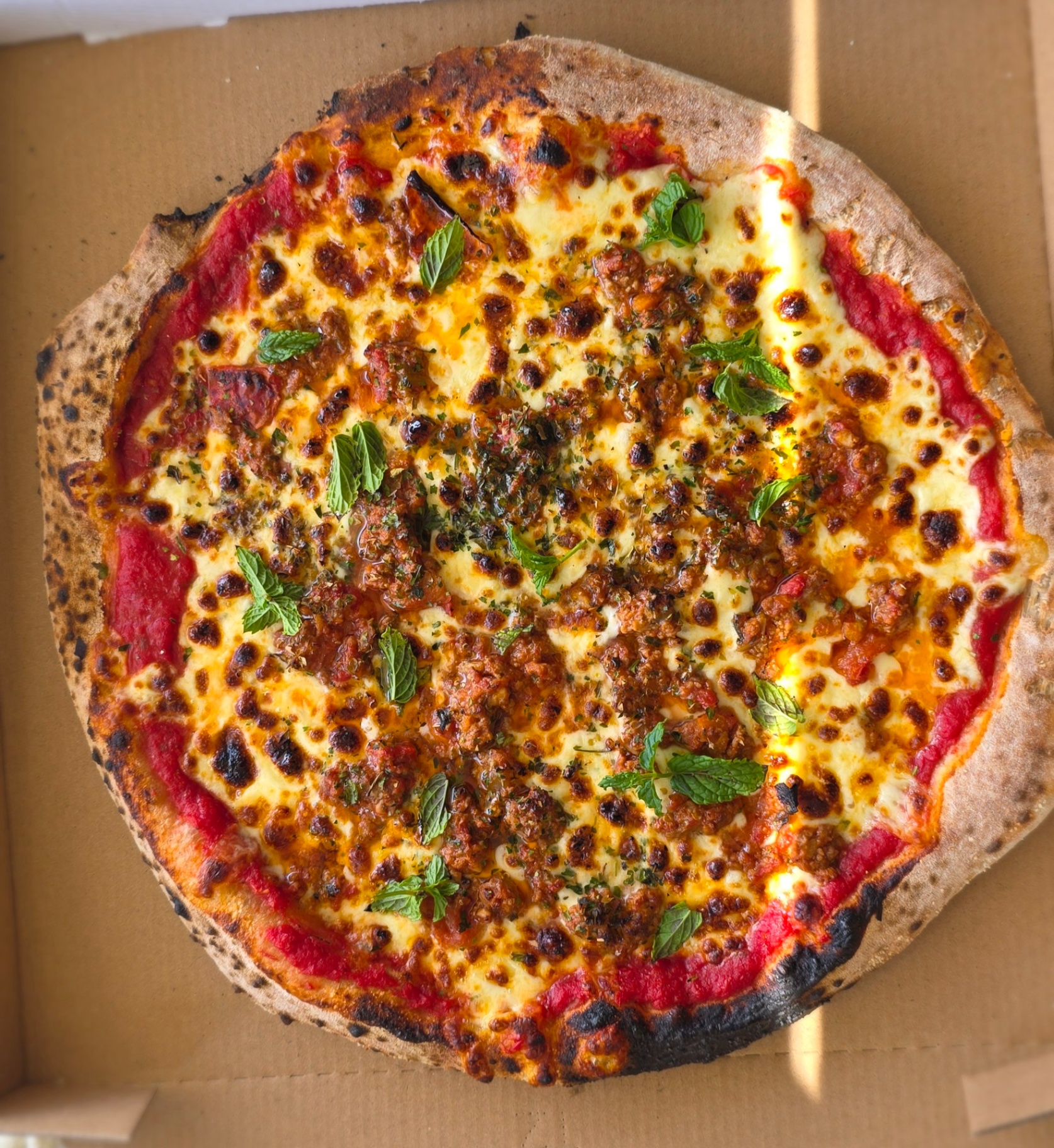Pizza with ragù and fresh mint